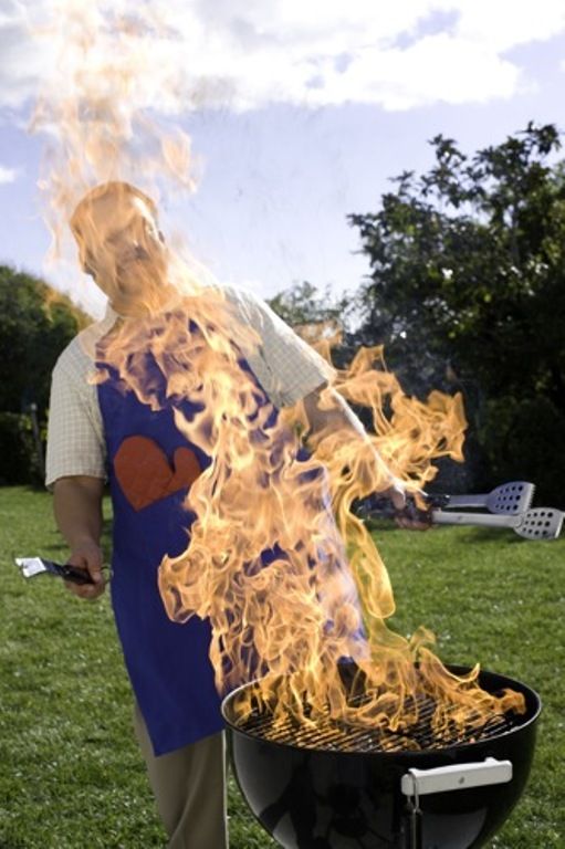 Man standing by large flame on grill